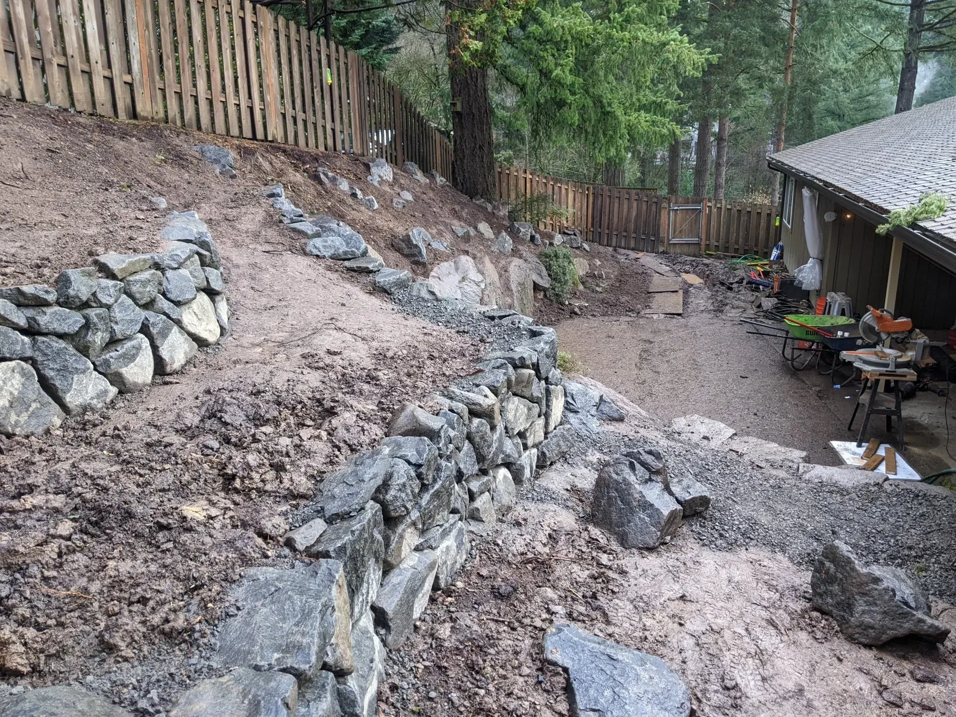 A backyard with newly constructed stone retaining walls on a slope.