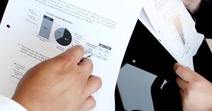 A person is looking at charts and data on a piece of paper. 