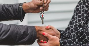 A person is handing keys over to another person.
