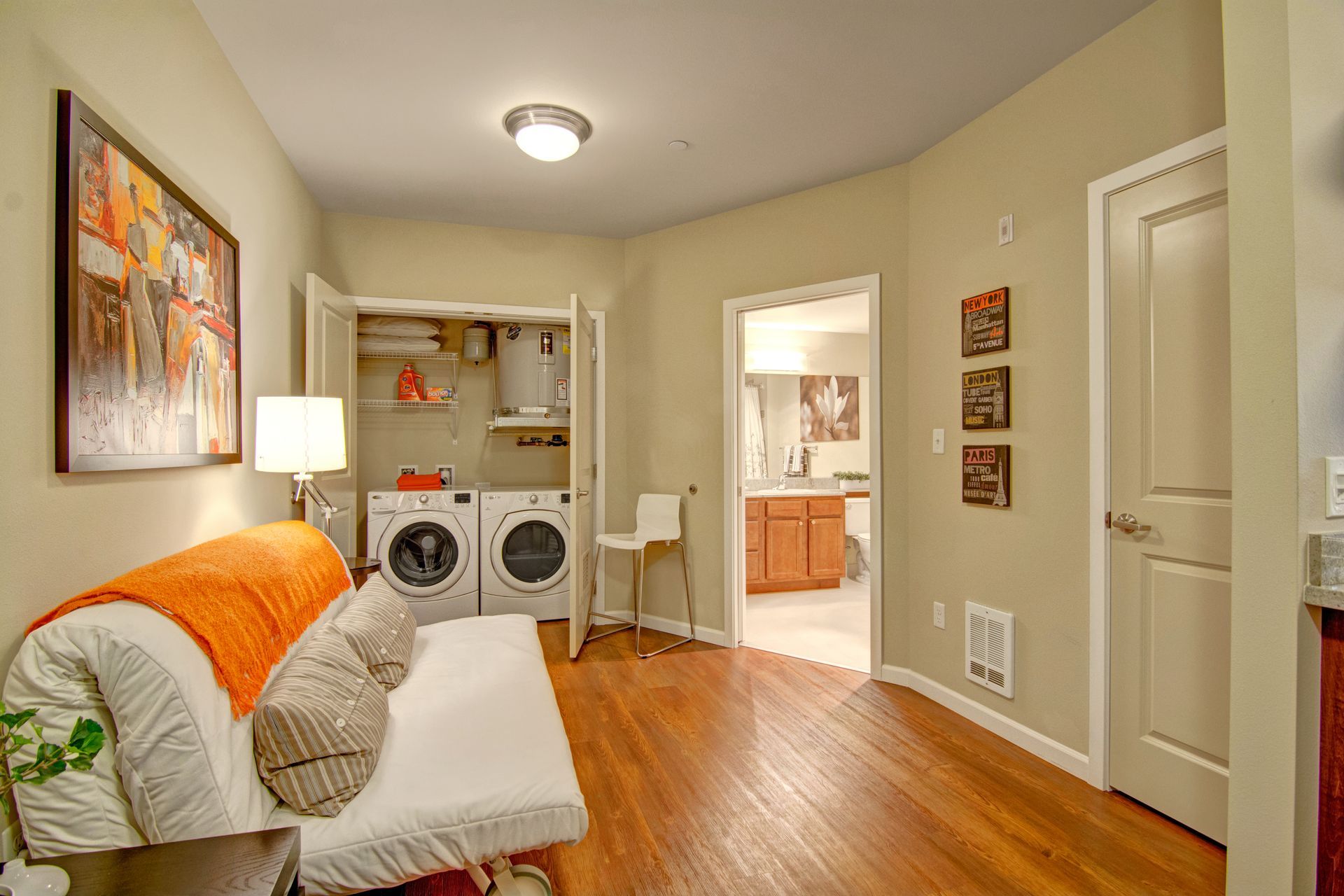 A laundry room with a futon and a washer and dryer.
