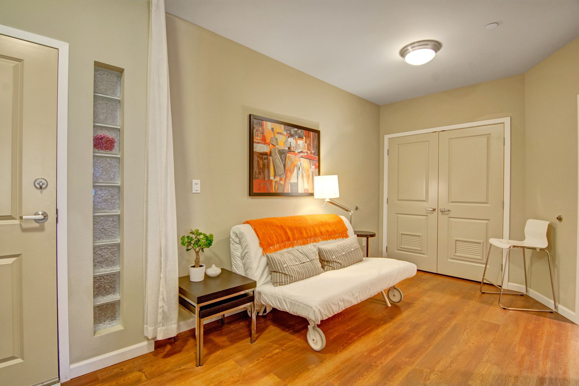 A living room with hardwood floors , a couch and a chair.