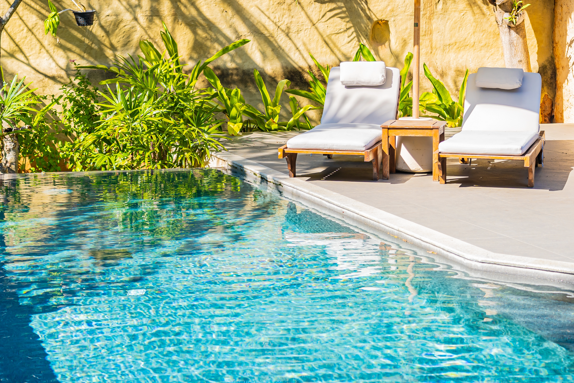 Swimming pool with blue water, surrounded by green grass and lounge chairs.