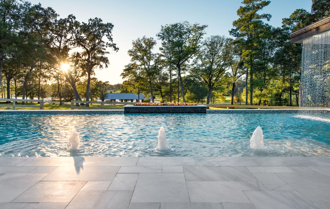 Water pouring into a clear blue swimming pool, creating ripples and splashes.