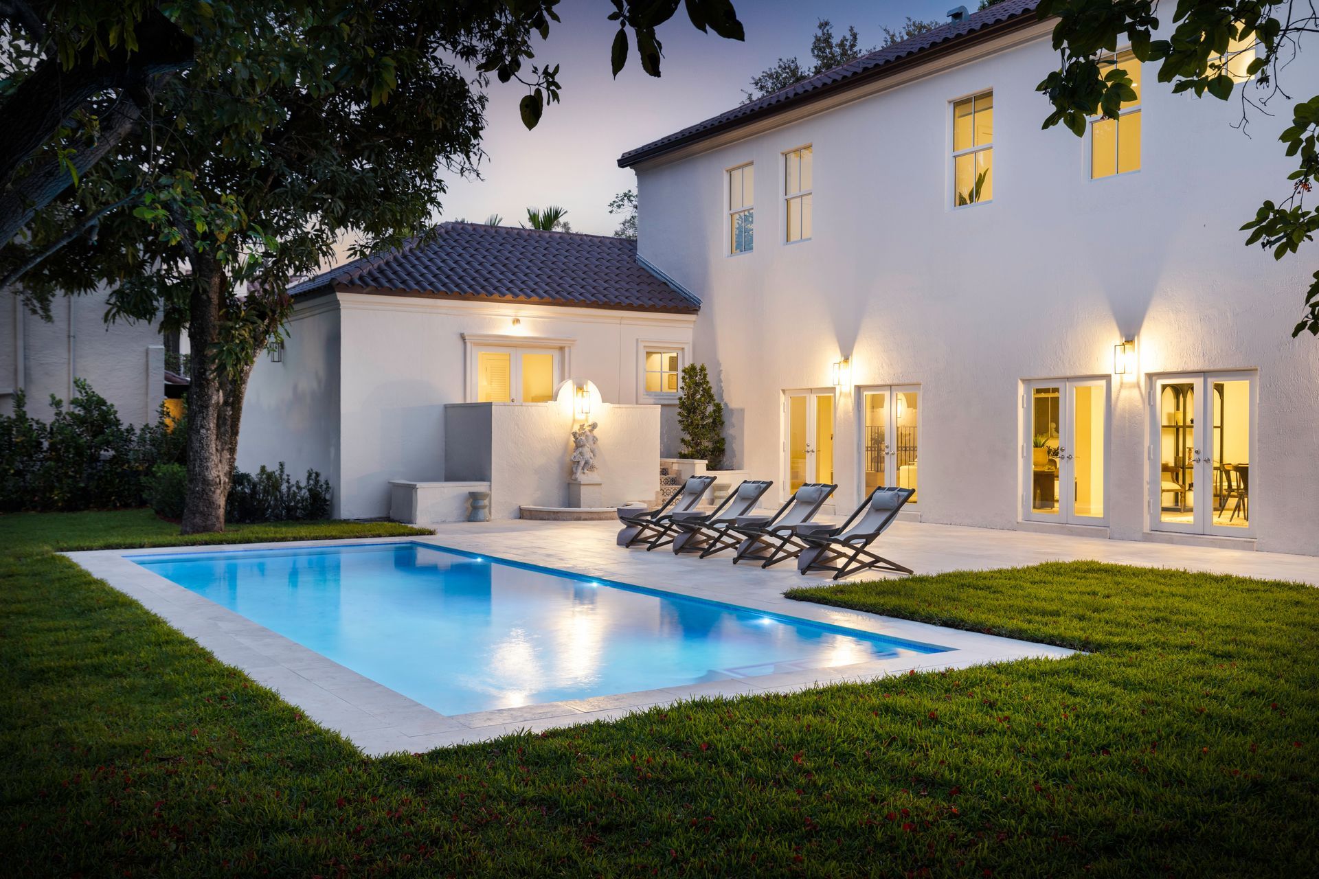 Aerial view of a swimming pool with a blue umbrella, lounge chairs, and landscaping.
