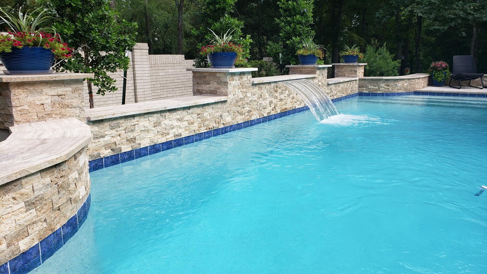 Pool with cascading water features flowing into the blue water, lawn in background.