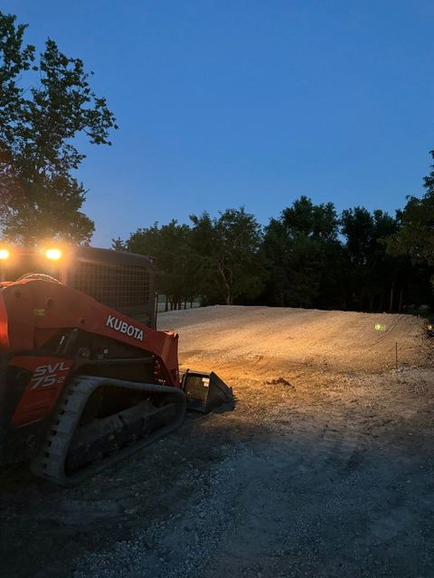 A bulldozer is driving down a dirt road at night.