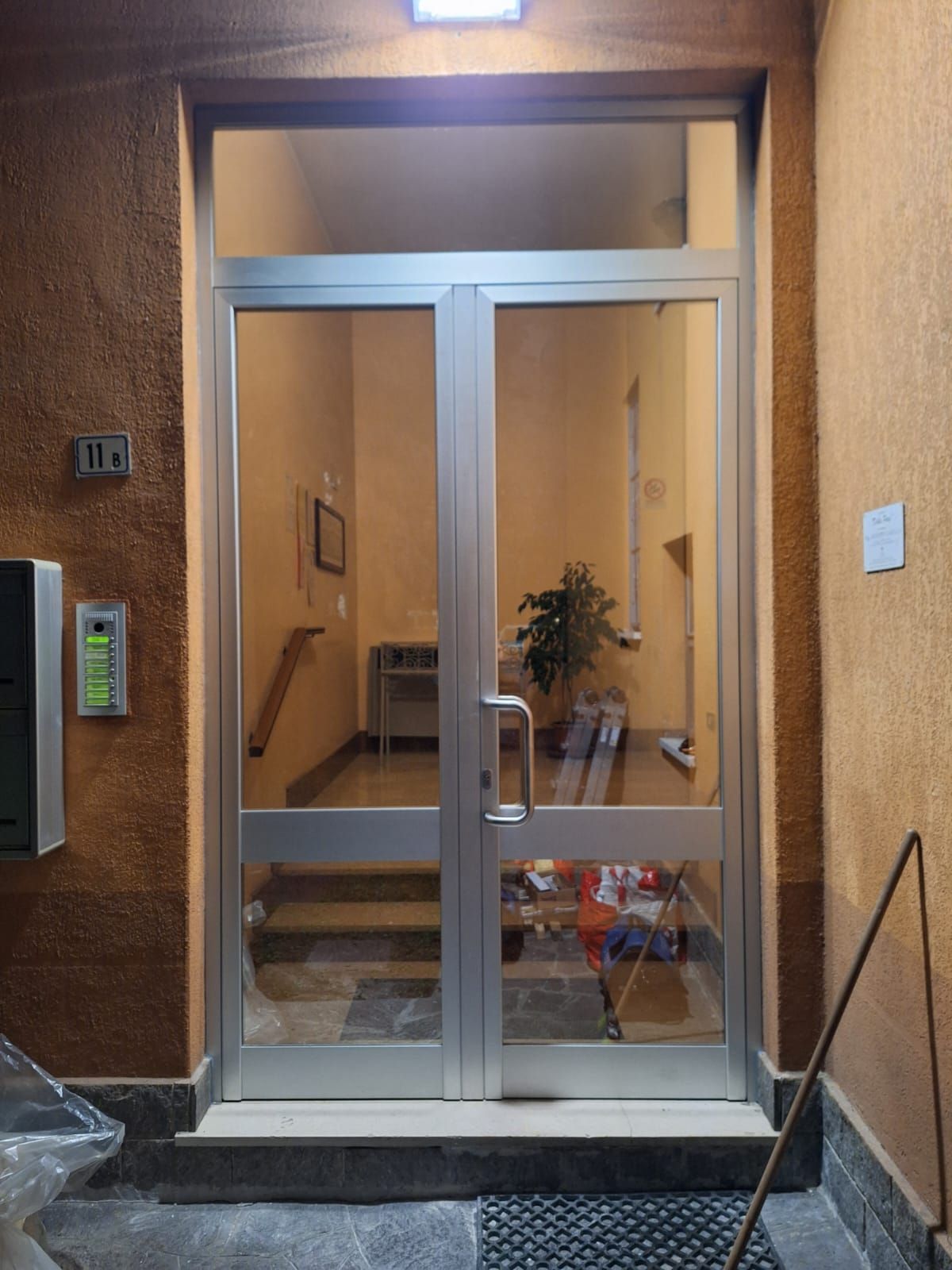 Doppie porte in vetro con telaio in alluminio che conducono all'ingresso di un edificio. 