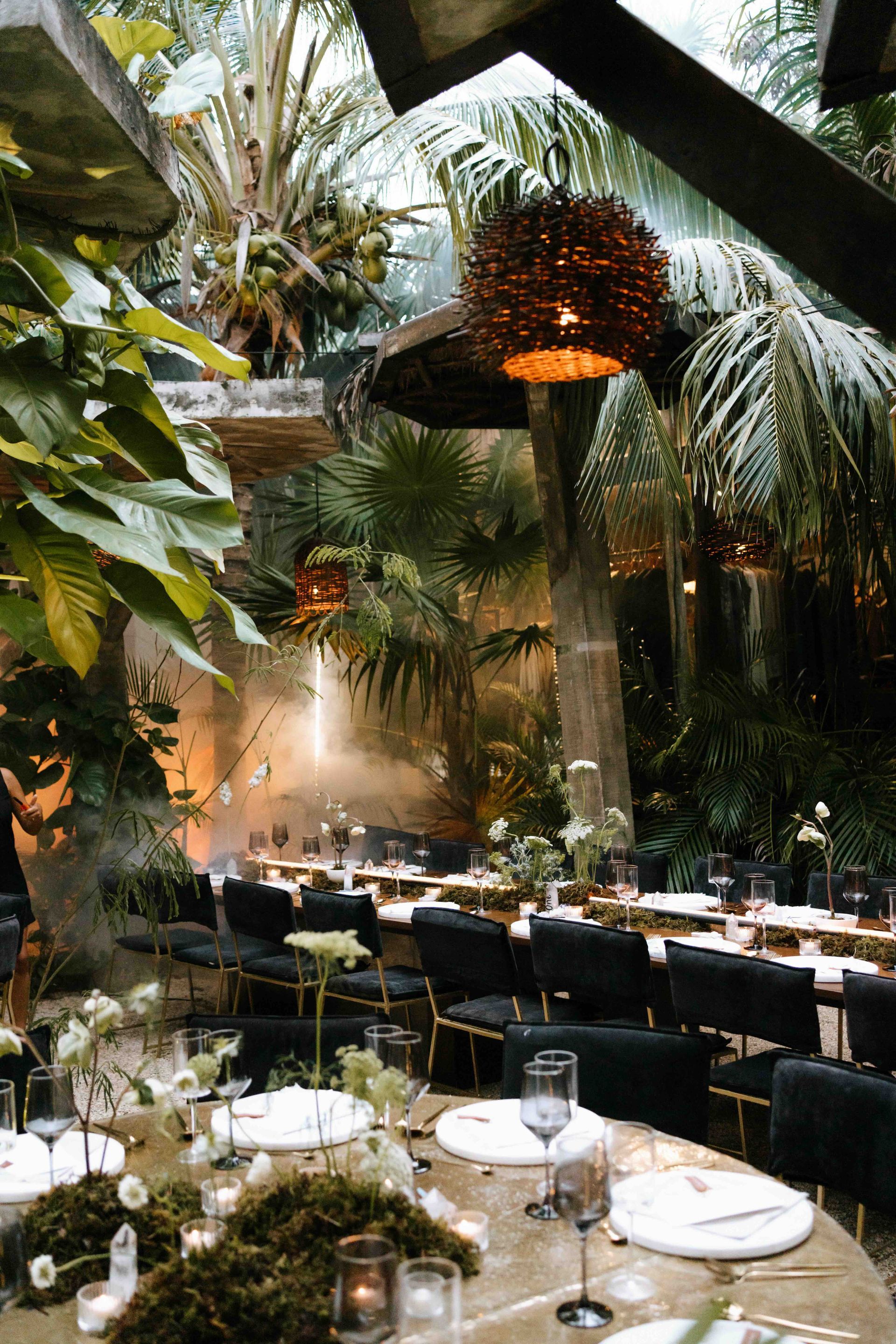 A restaurant filled with tables and chairs surrounded by trees and plants.