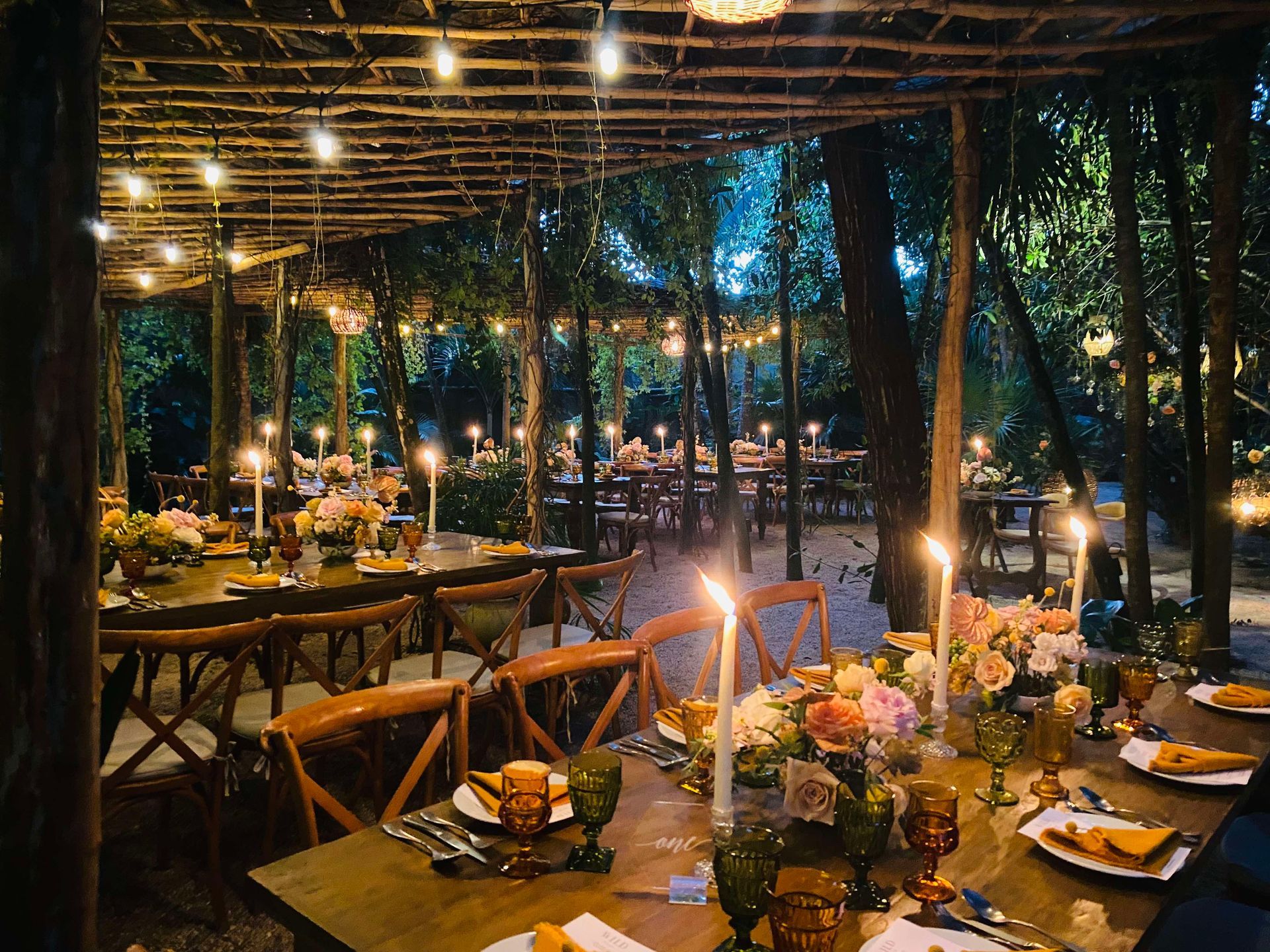 A table set for a wedding reception with candles and flowers on it.