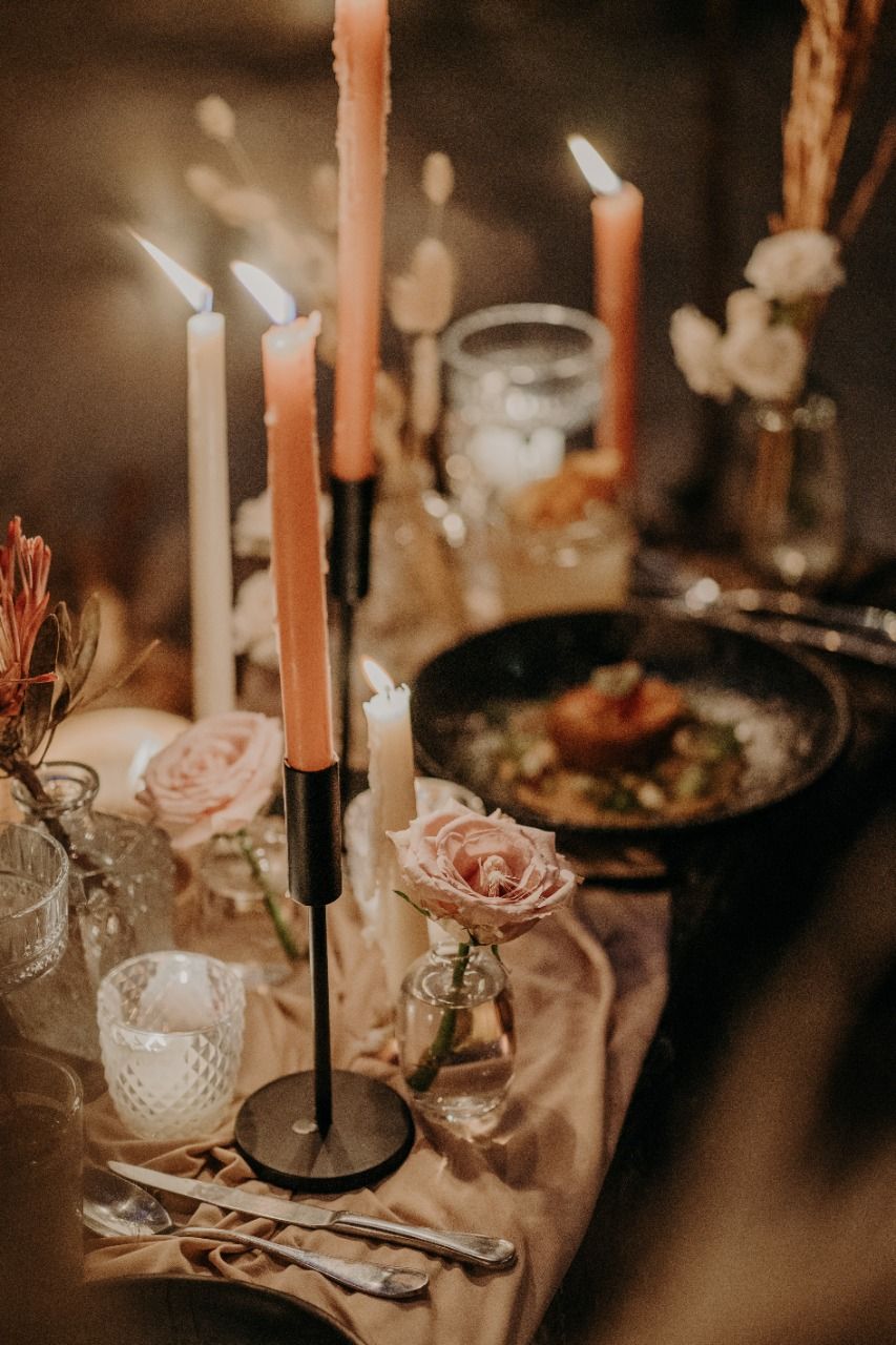 A table with candles , flowers , and food on it.