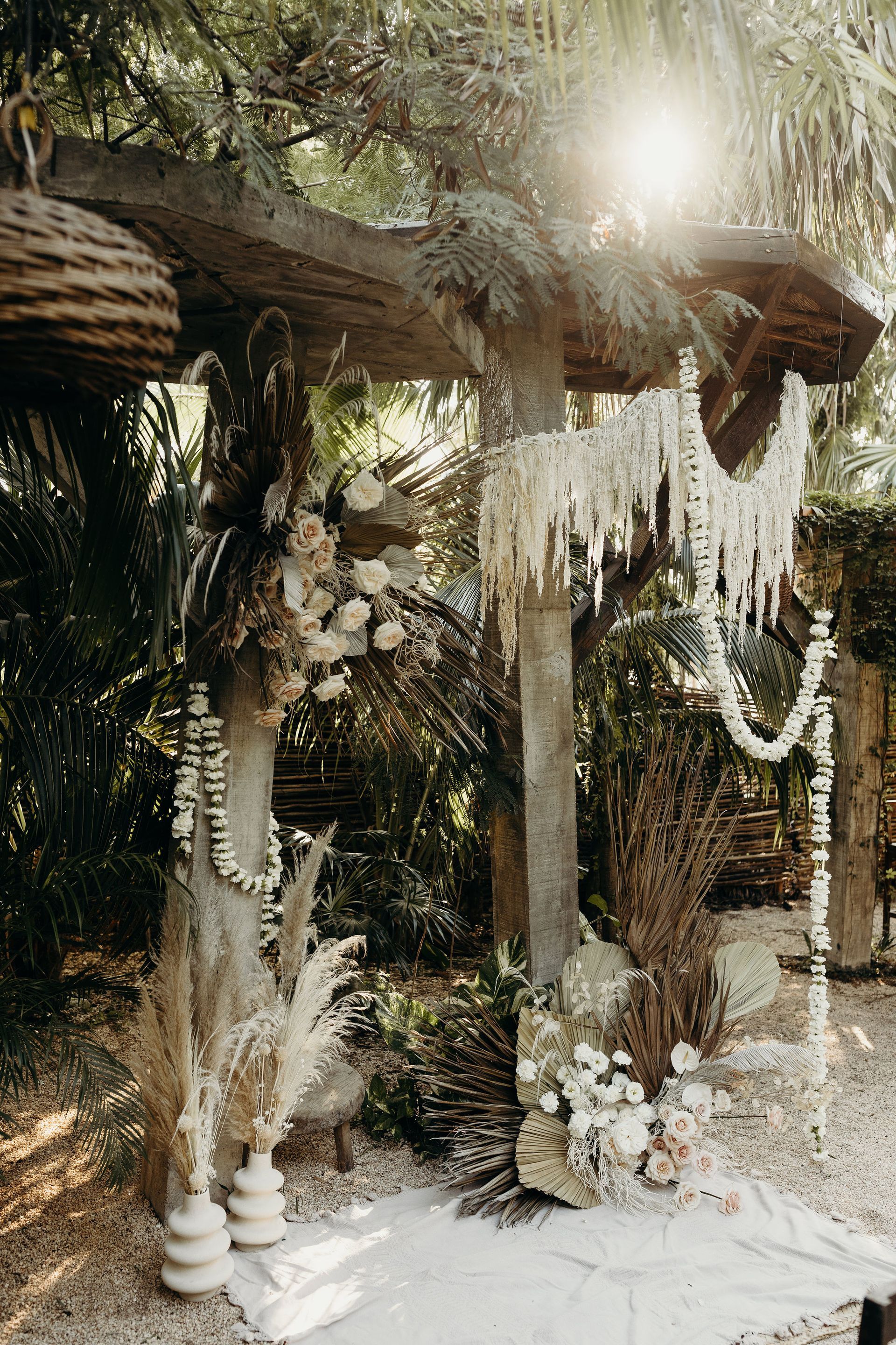 A wedding arch decorated with flowers and candles in the woods.