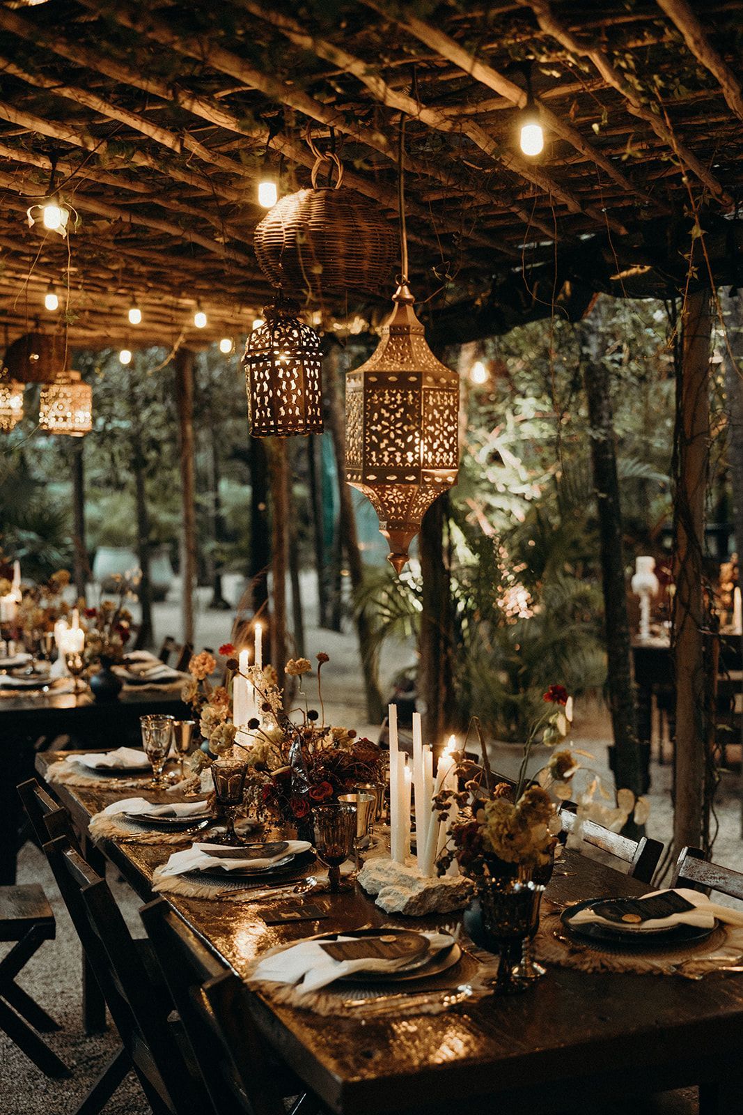 A long table with candles and lanterns hanging from the ceiling.