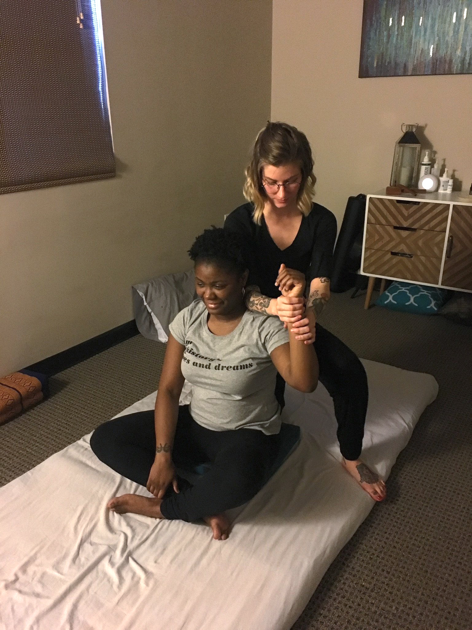 A woman is giving a massage to another woman on a bed.