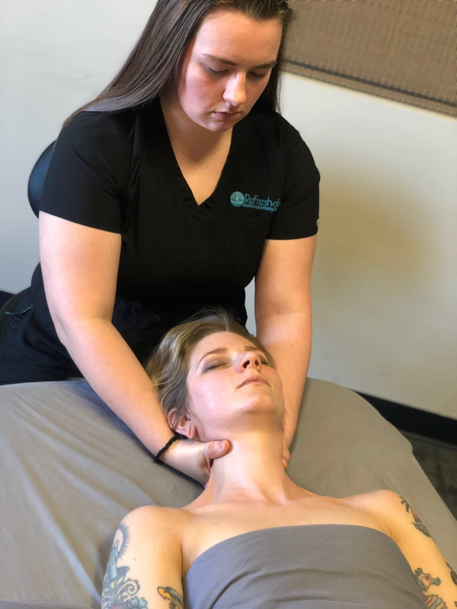 A woman is giving a massage to a woman laying on a bed.