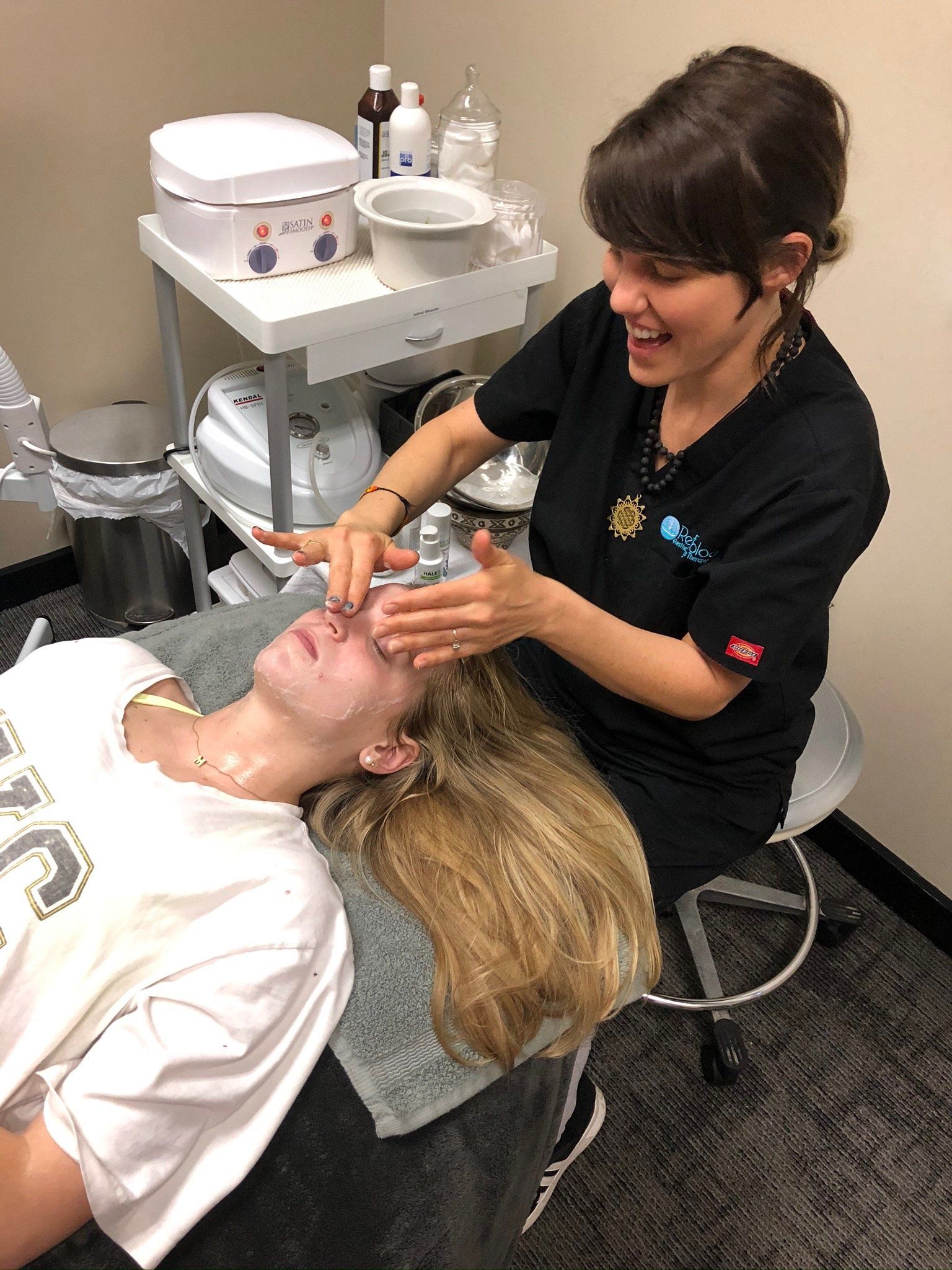 A woman is giving a woman a facial treatment in a salon.