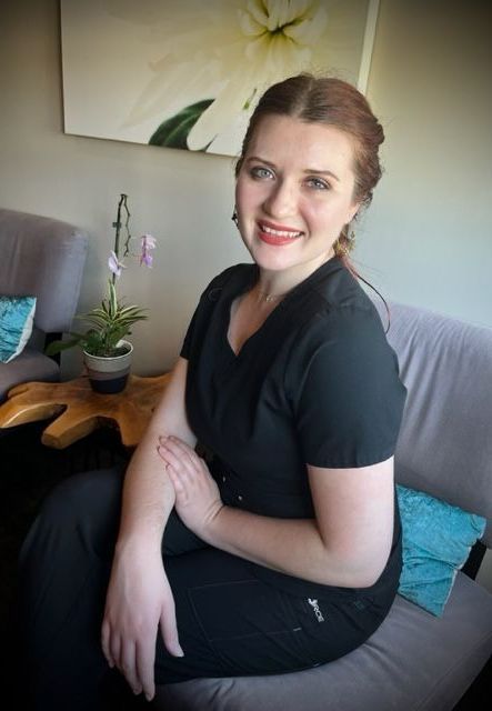 A woman with her hair back is sitting and smiling