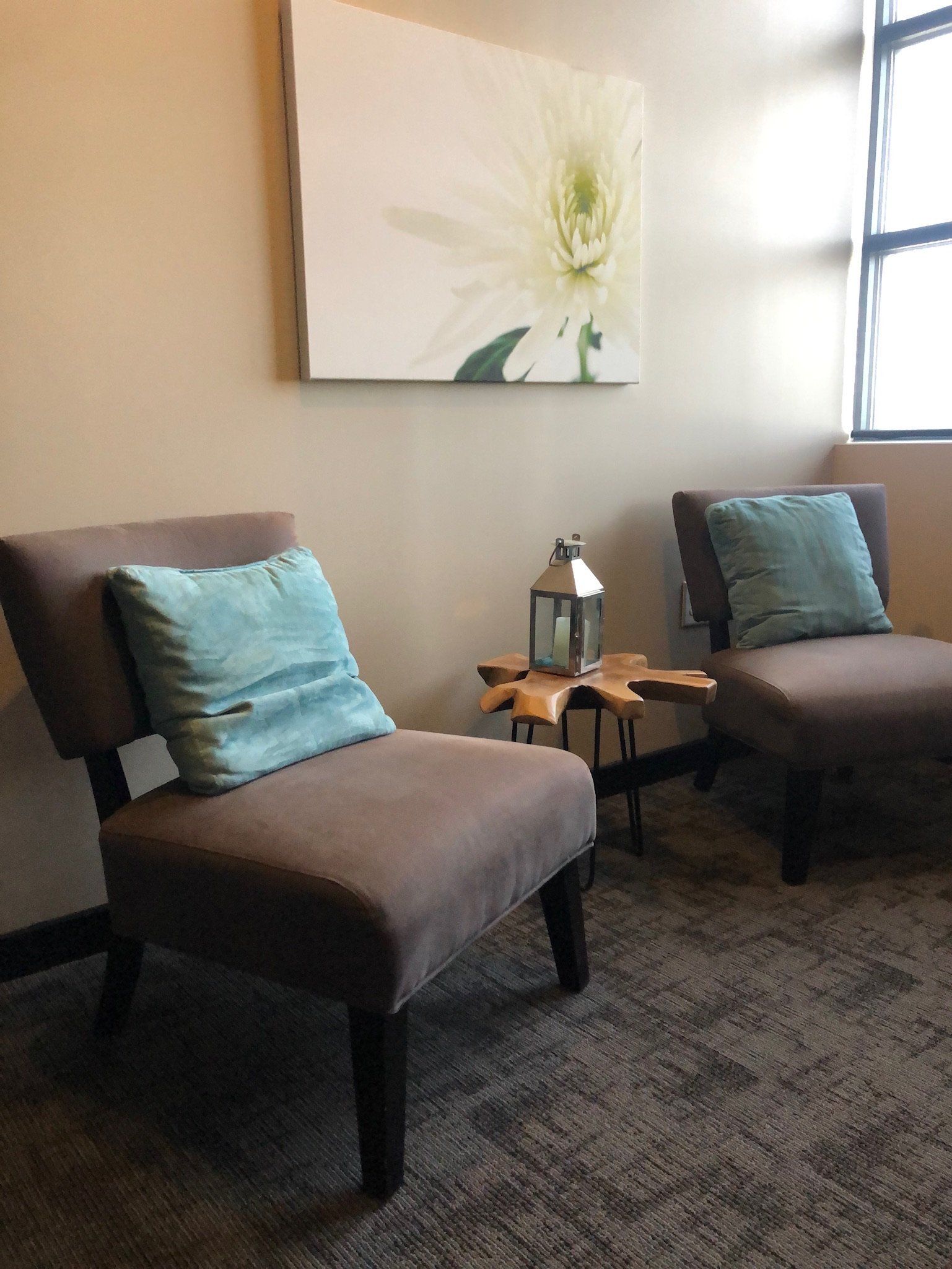 Two chairs and a table in a room with a painting on the wall.