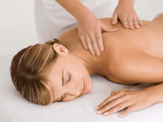 A woman is laying on a table getting a massage.