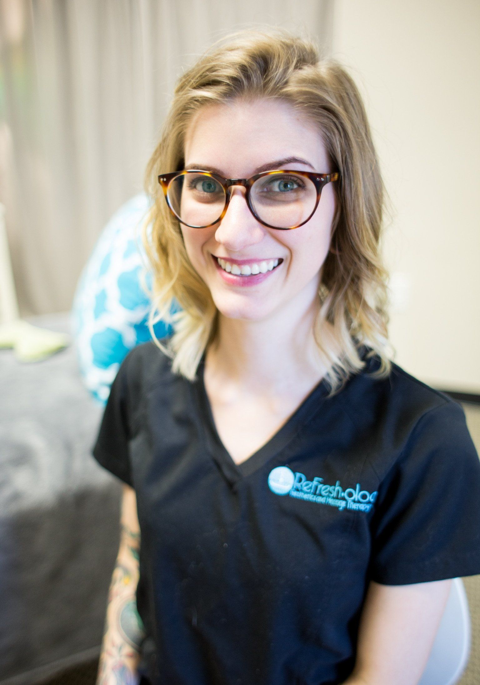 A woman wearing glasses and a black shirt is smiling for the camera.