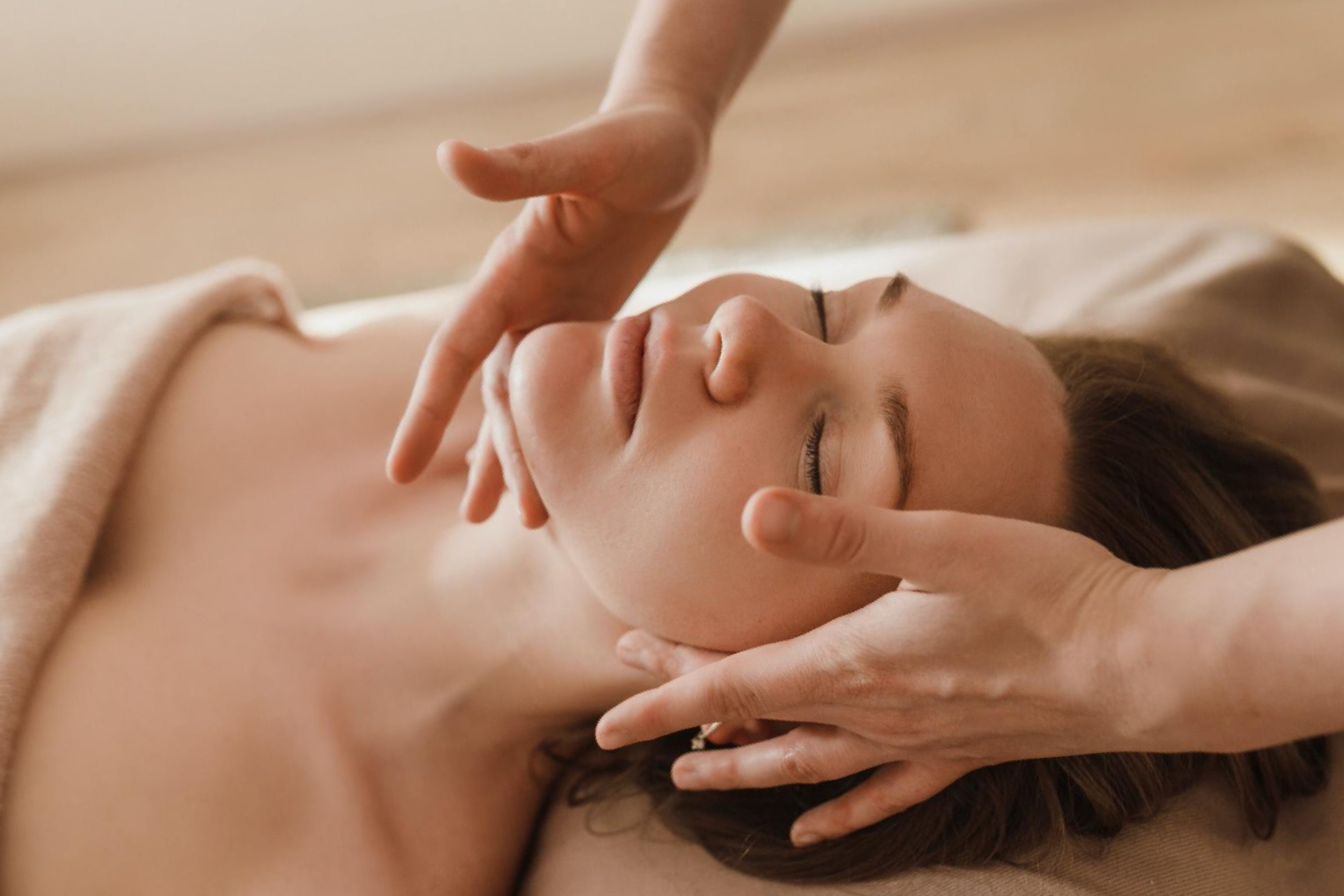 A woman is getting a facial massage at a spa.