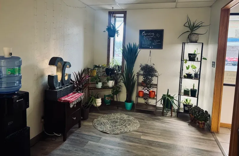 Living room with many potted plants, a water cooler, and an open doorway to outside.