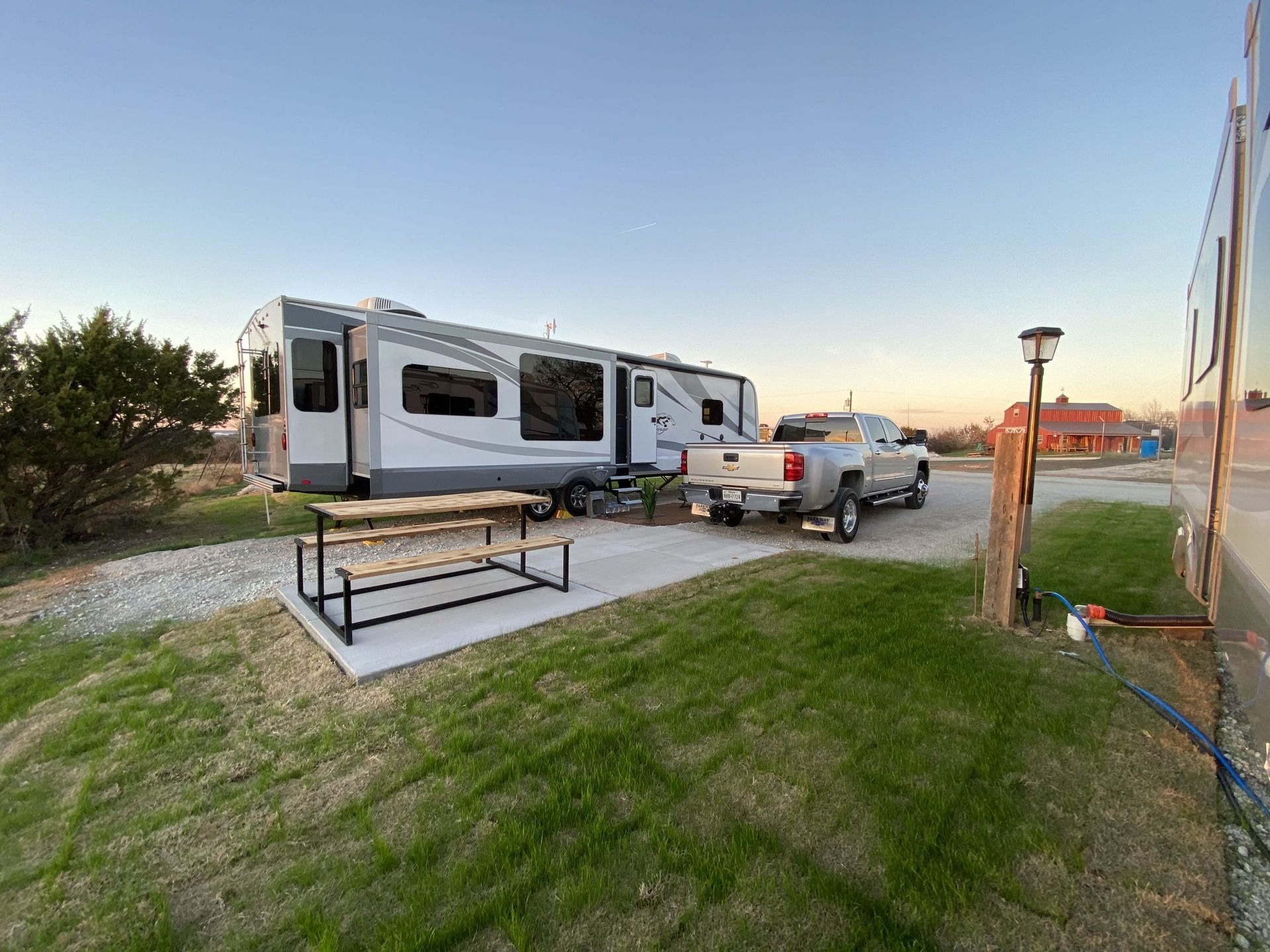 RV and truck parked at campsite with picnic table; green grass and gravel.