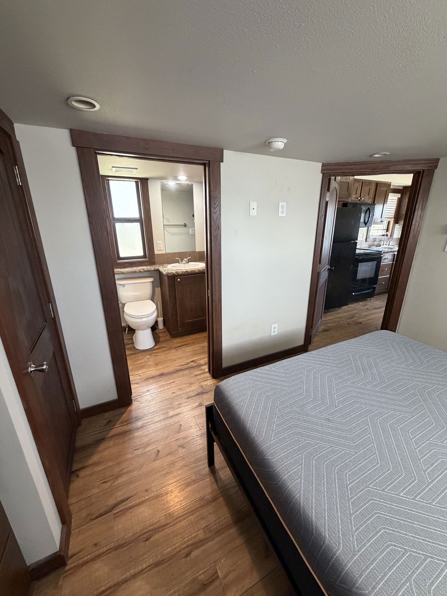 Small bedroom with a bed, attached bathroom, and hallway view through a doorway