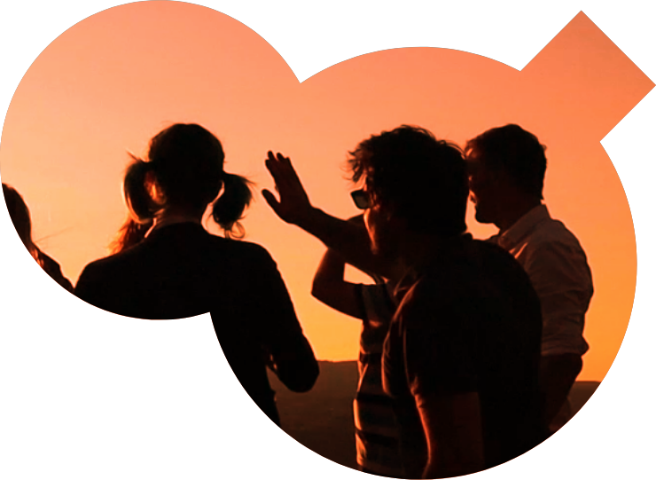 Des silhouettes contemplent le coucher du soleil. Une personne lève la main.