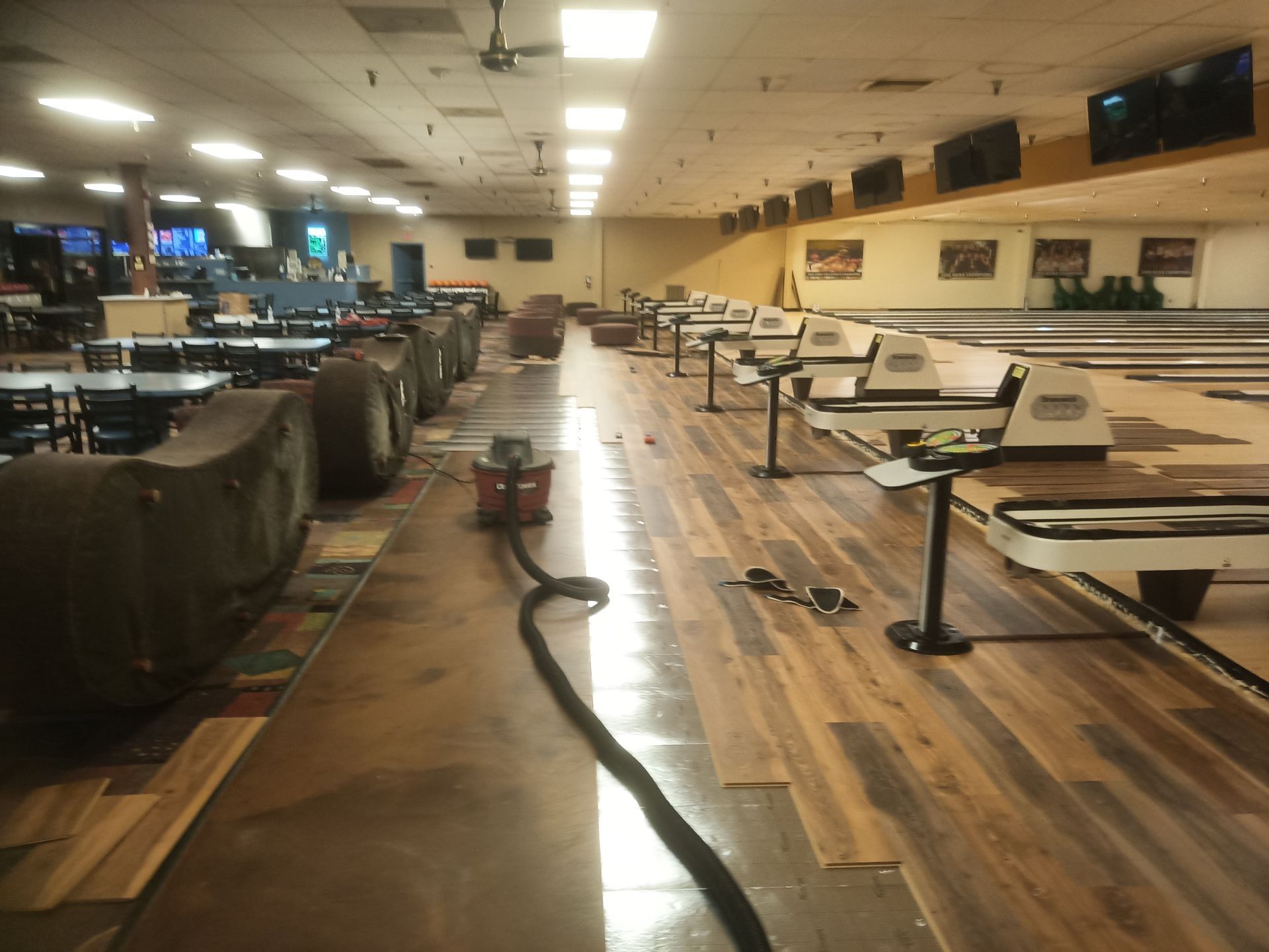 Bowling alley with lanes, ball returns, and seating under bright overhead lights.