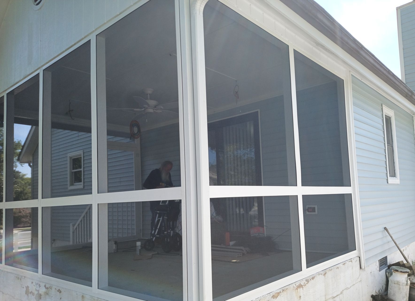 Screened porch with white trim on a light blue house, viewed from the corner.