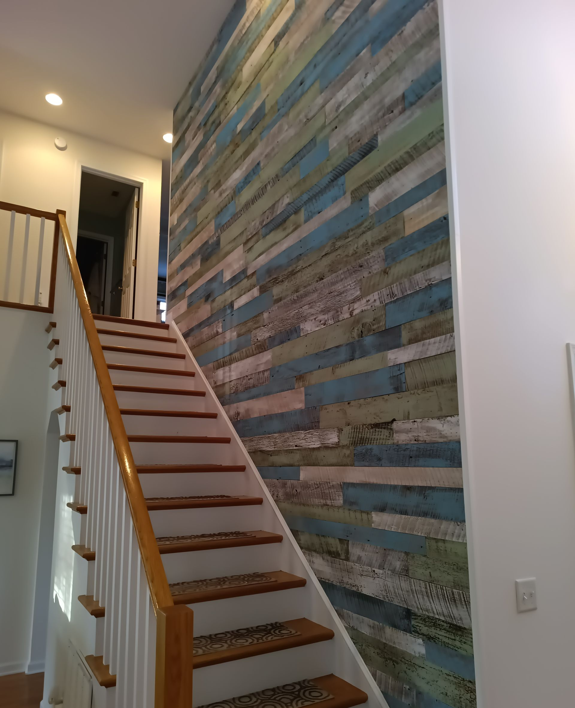Indoor staircase beside a tall multicolored brick accent wall in a home hallway