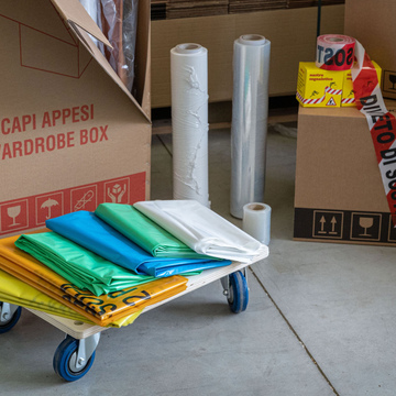 Carrello carico di coperte da trasloco colorate e scatole in un’area di deposito