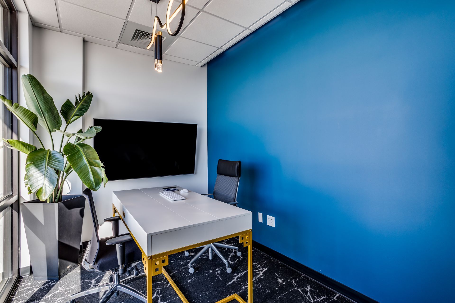 A conference room with blue walls , a table , chairs and a flat screen tv.