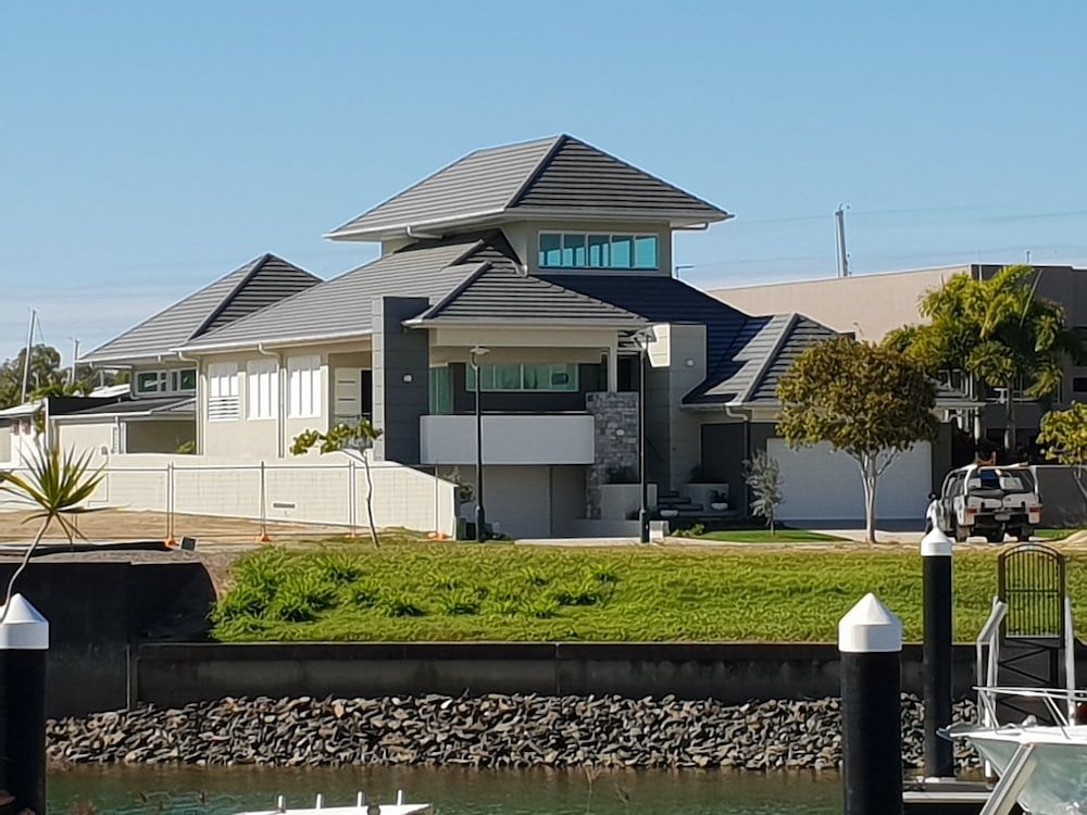 A Large House Sits Next to a Body of Water — High Performance Roof Tiling P/L in Townsville, QLD