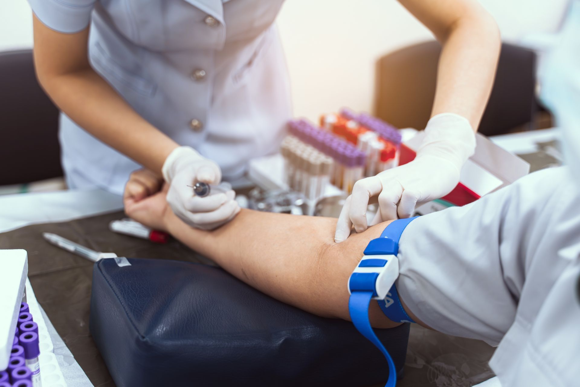 Person getting blood drawn at a medical clinic, with tubes and equipment visible.