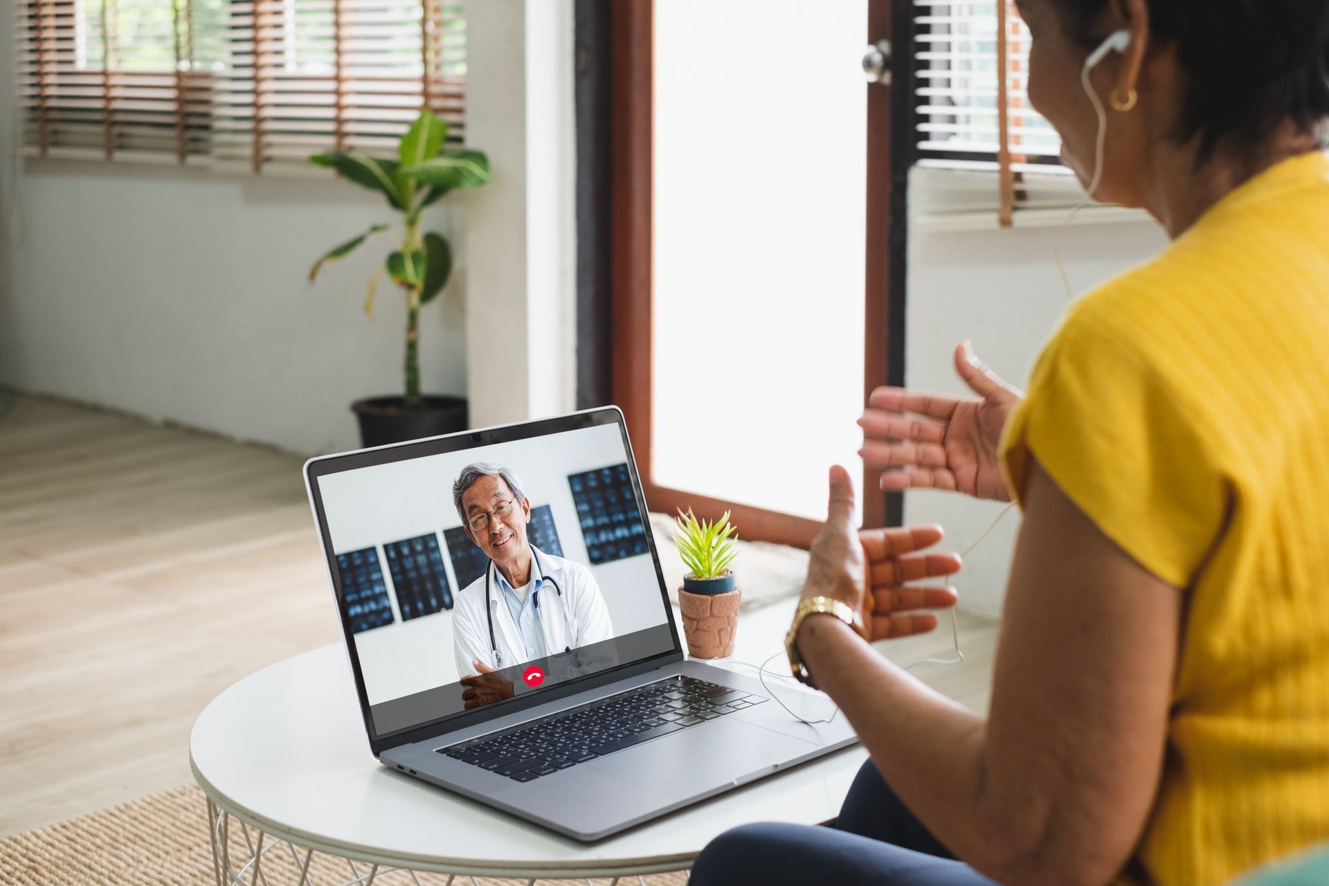 Woman using laptop for telehealth appointment with doctor.