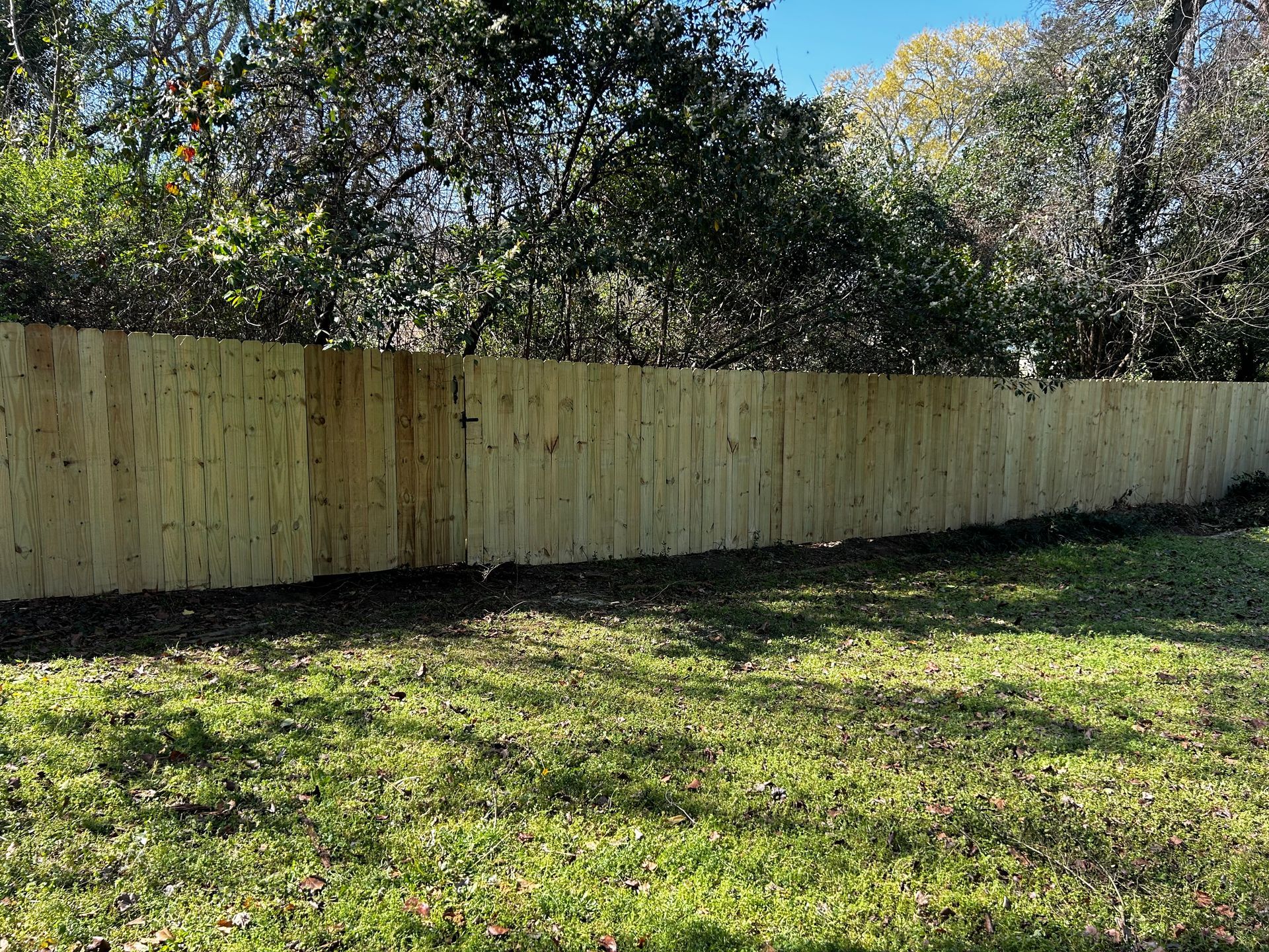 A wooden fence is in the middle of a lush green field.