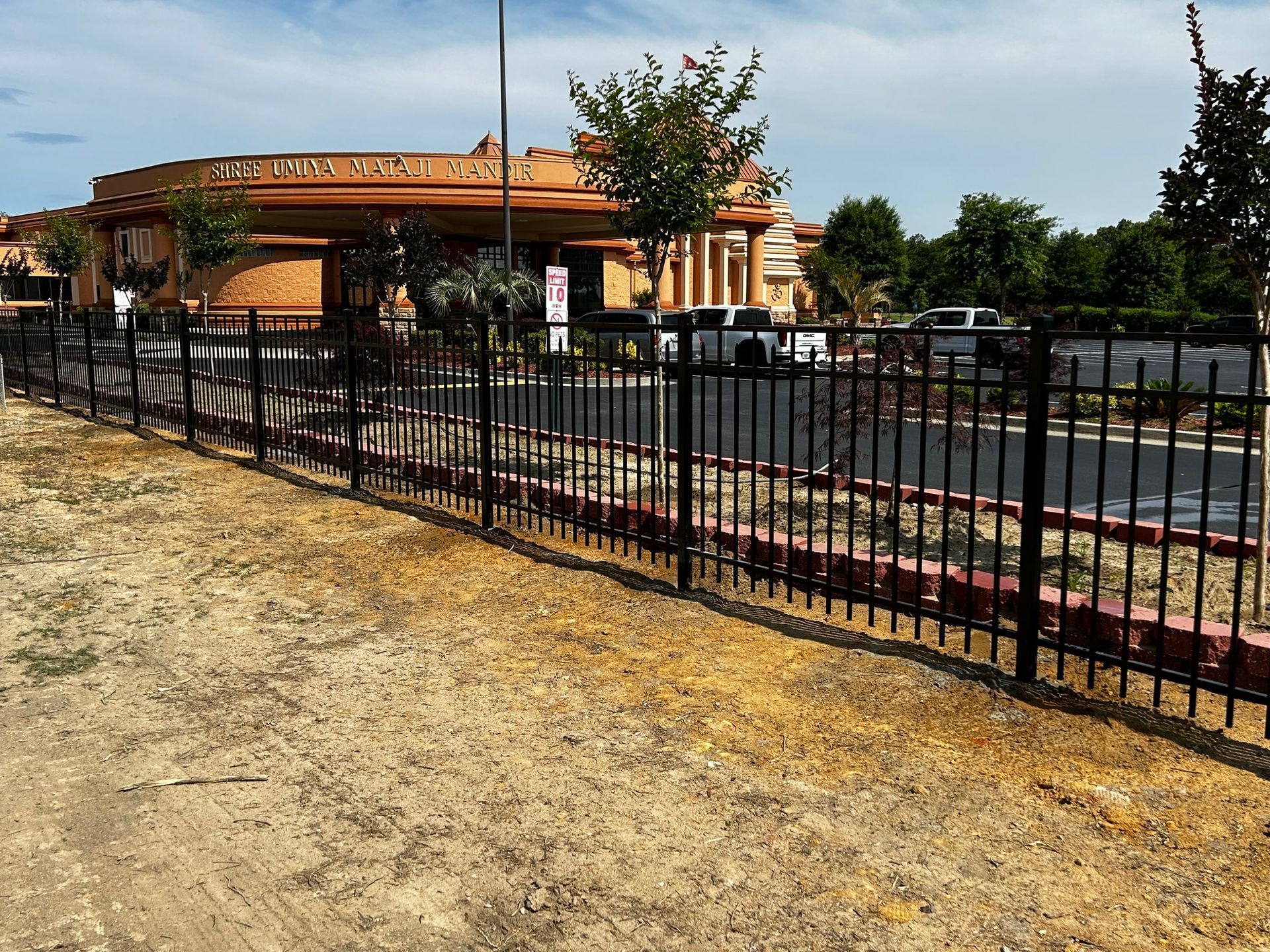 A black wrought iron fence surrounded by green plants.