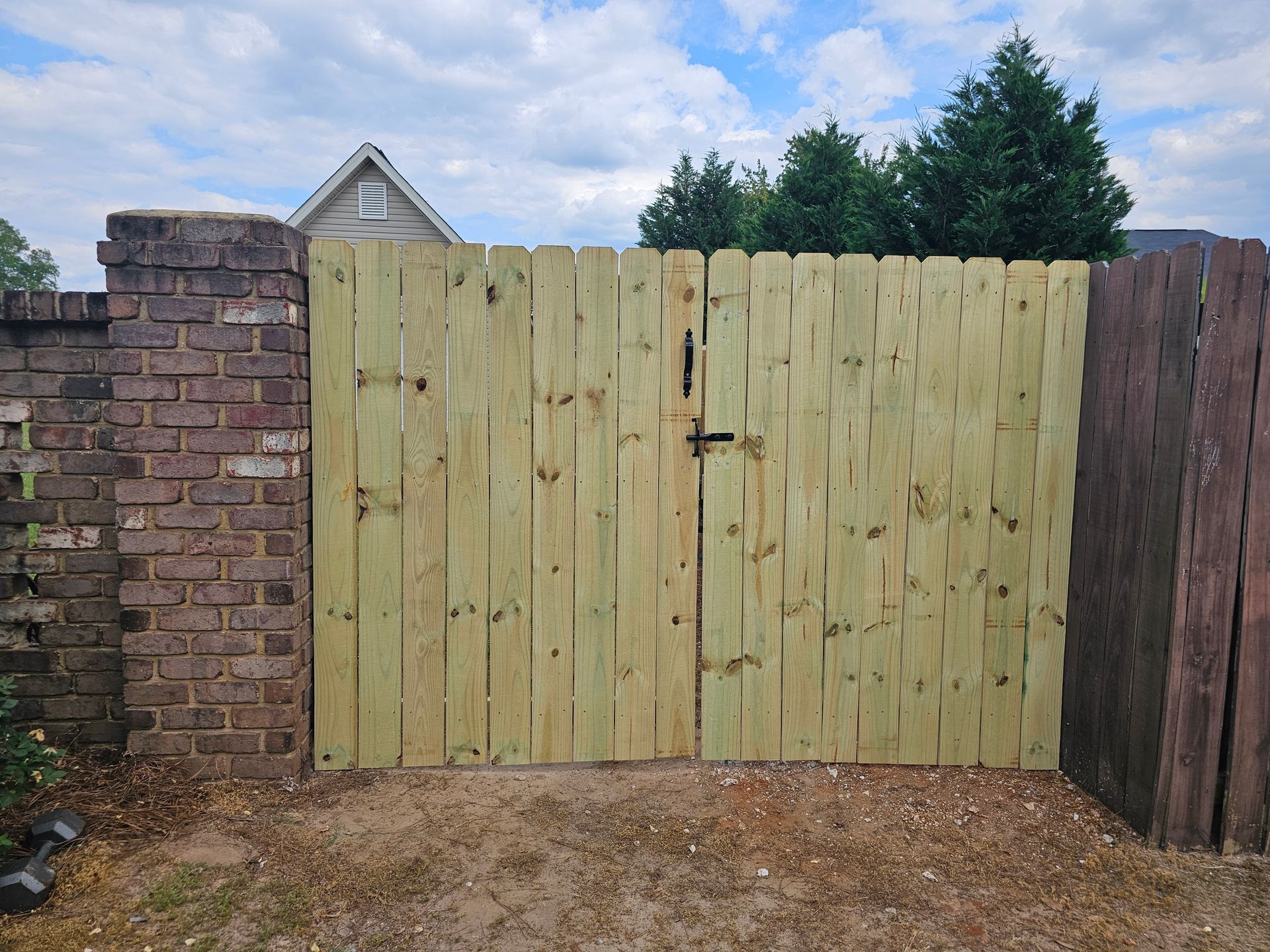 A wooden gate is sitting in front of a brick wall.