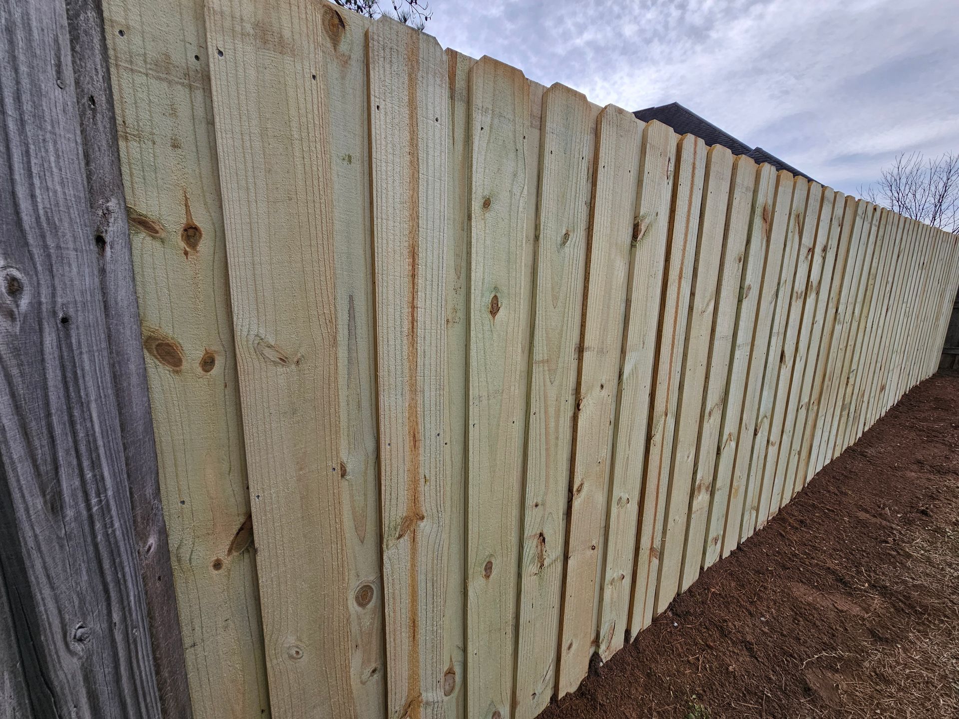 A wooden fence is sitting on top of a dirt field.