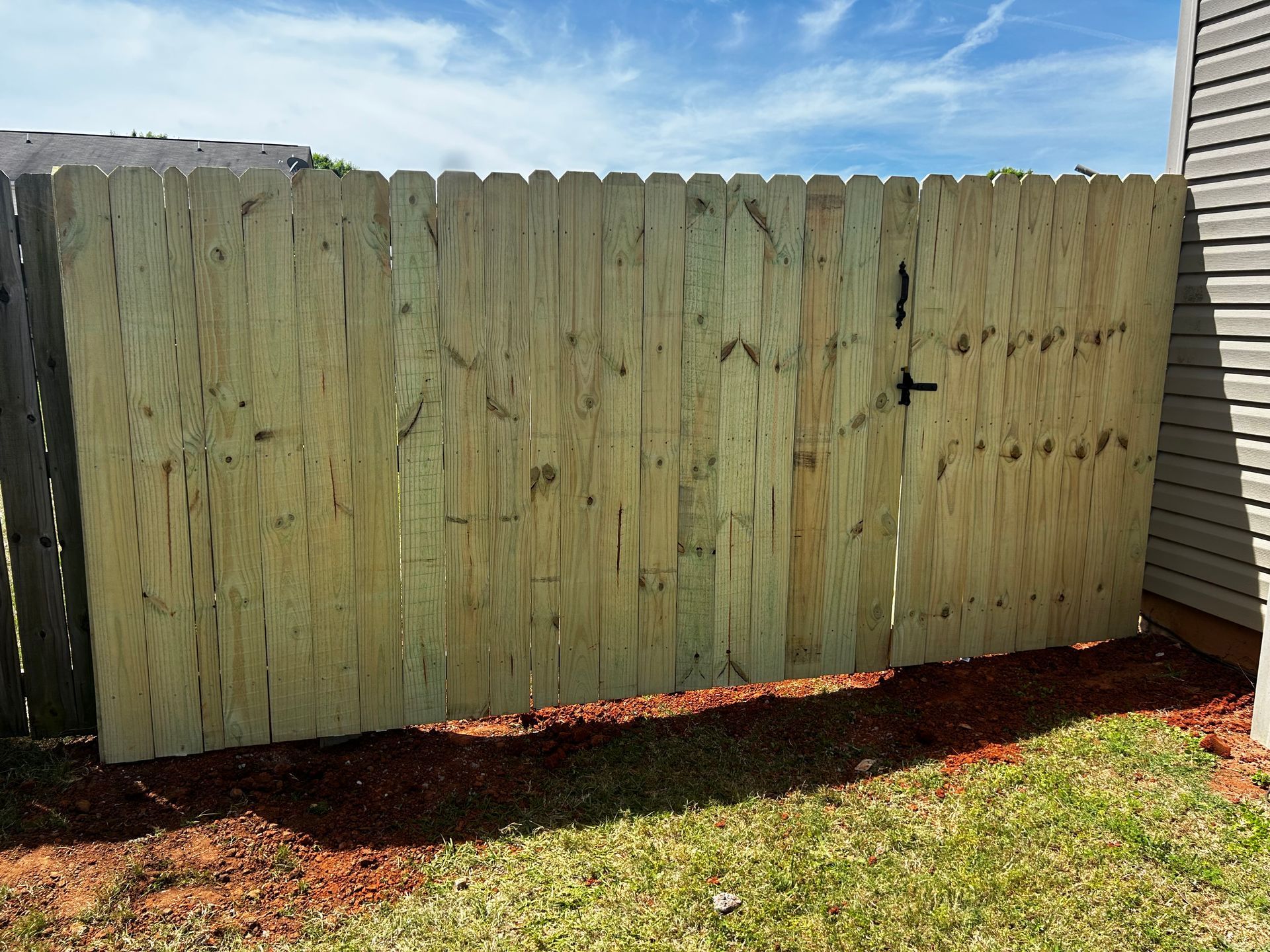 A wooden fence with a gate in the backyard of a house.