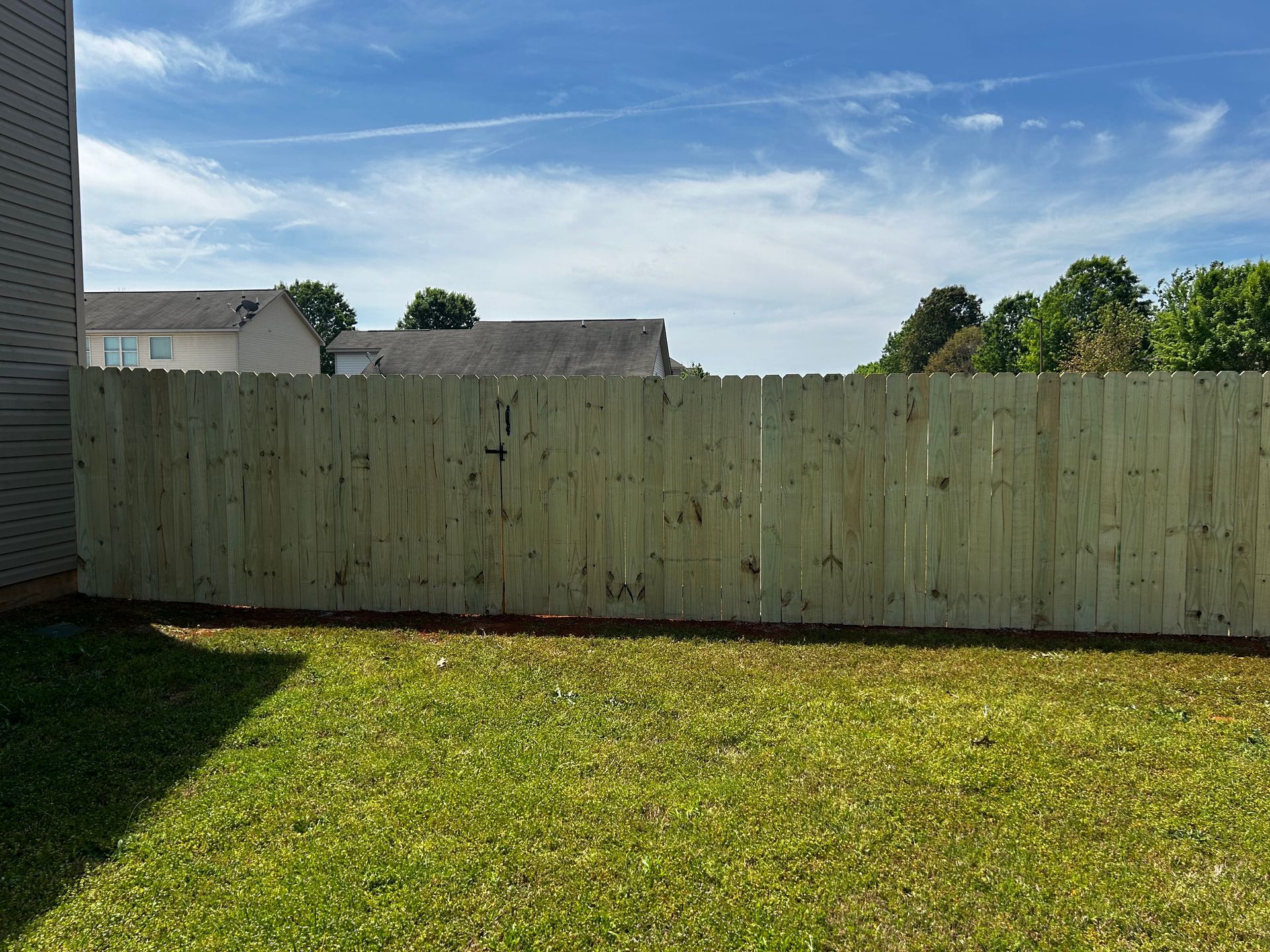 A wooden fence is in the backyard of a house.