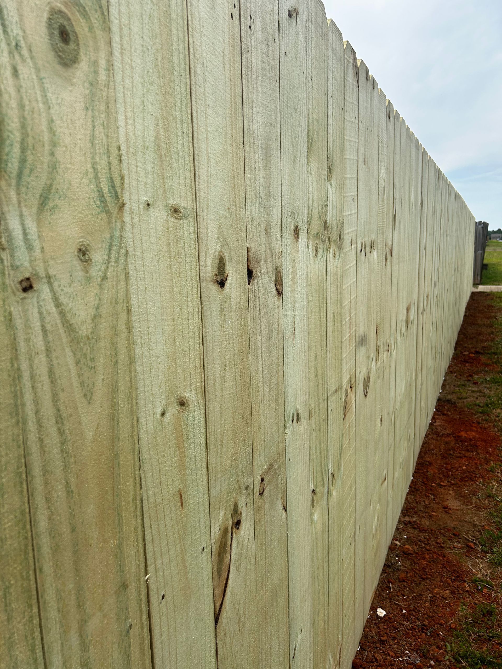 A long wooden fence is sitting on top of a dirt field.