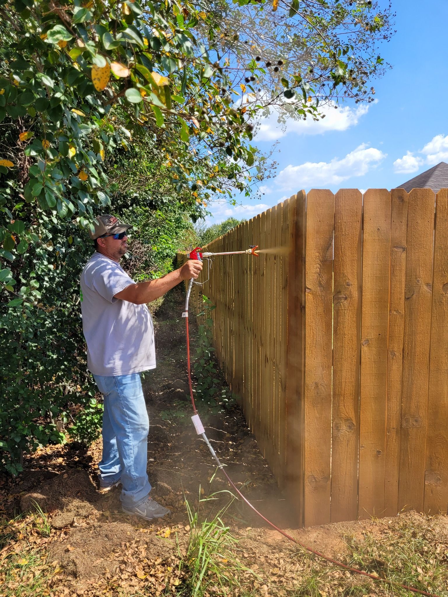 A man is spraying water on a wooden fence