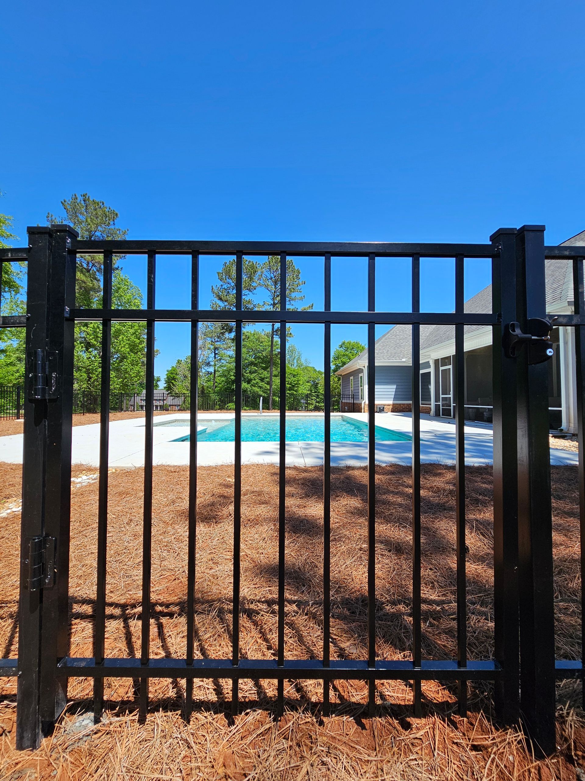 A black fence with a pool in the background