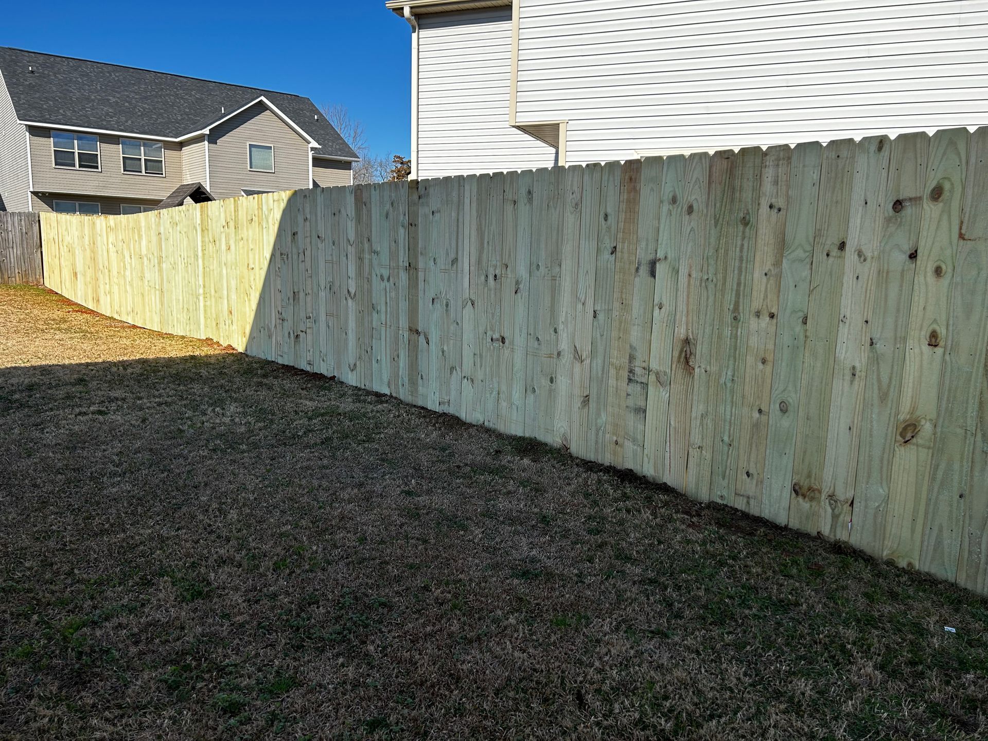A wooden fence is in the backyard of a house.