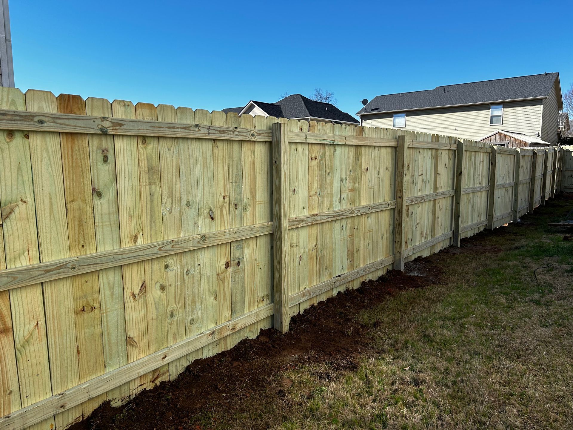 A wooden fence is in the backyard of a house.