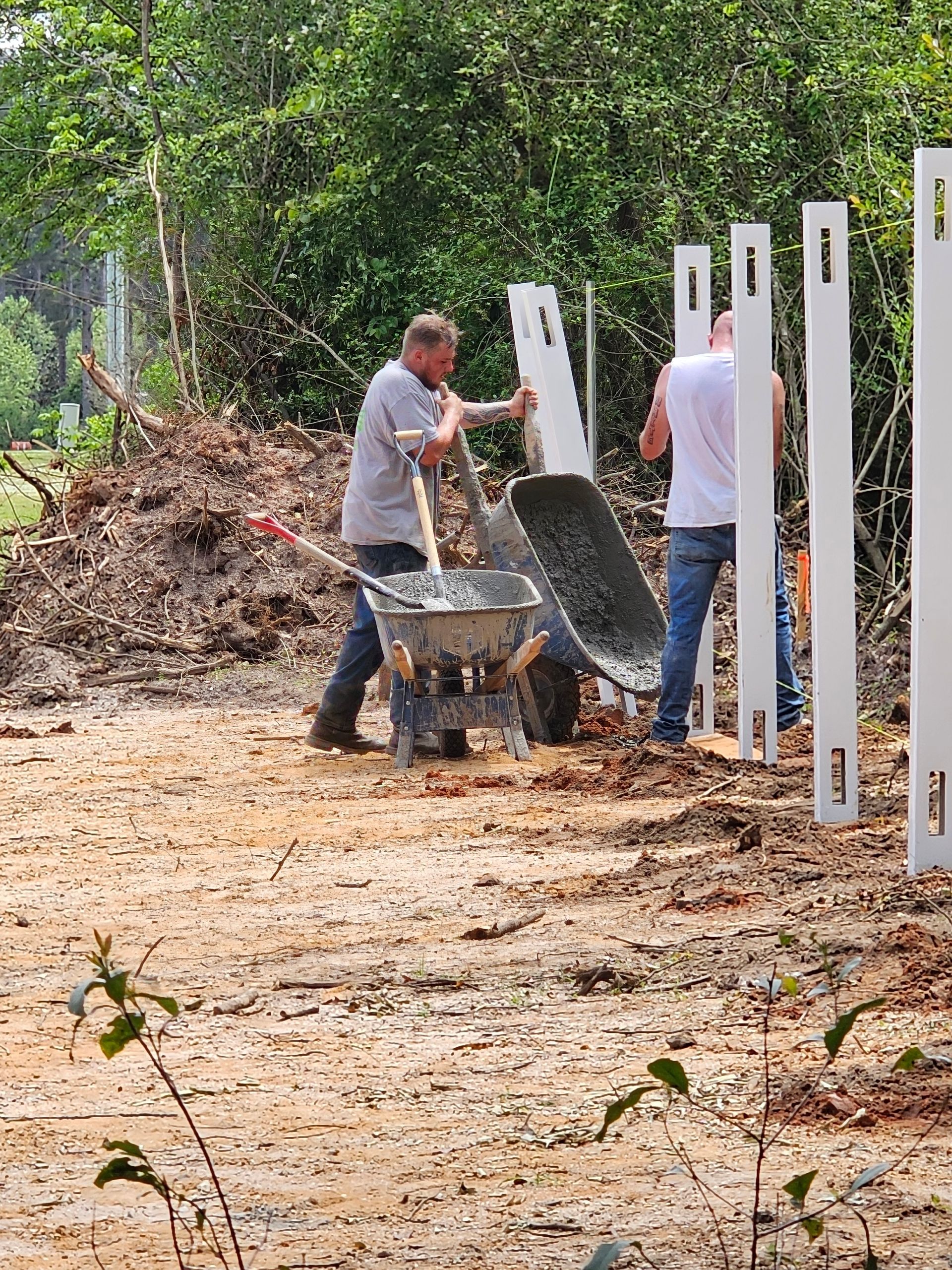 A man is pushing a wheelbarrow in a dirt field.