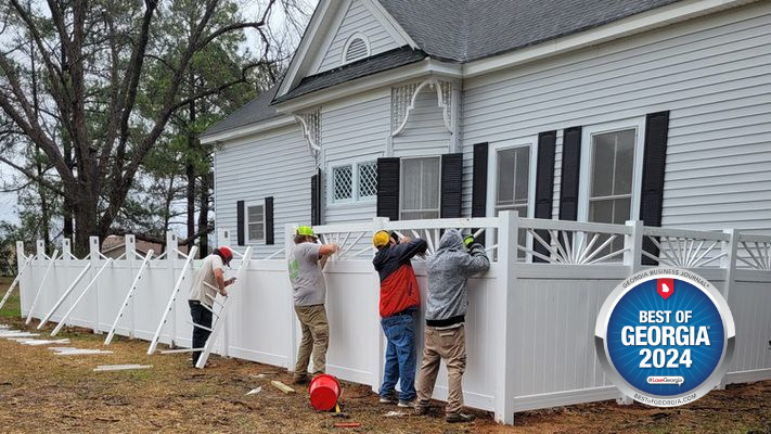A group of men are installing a fence in front of a house.