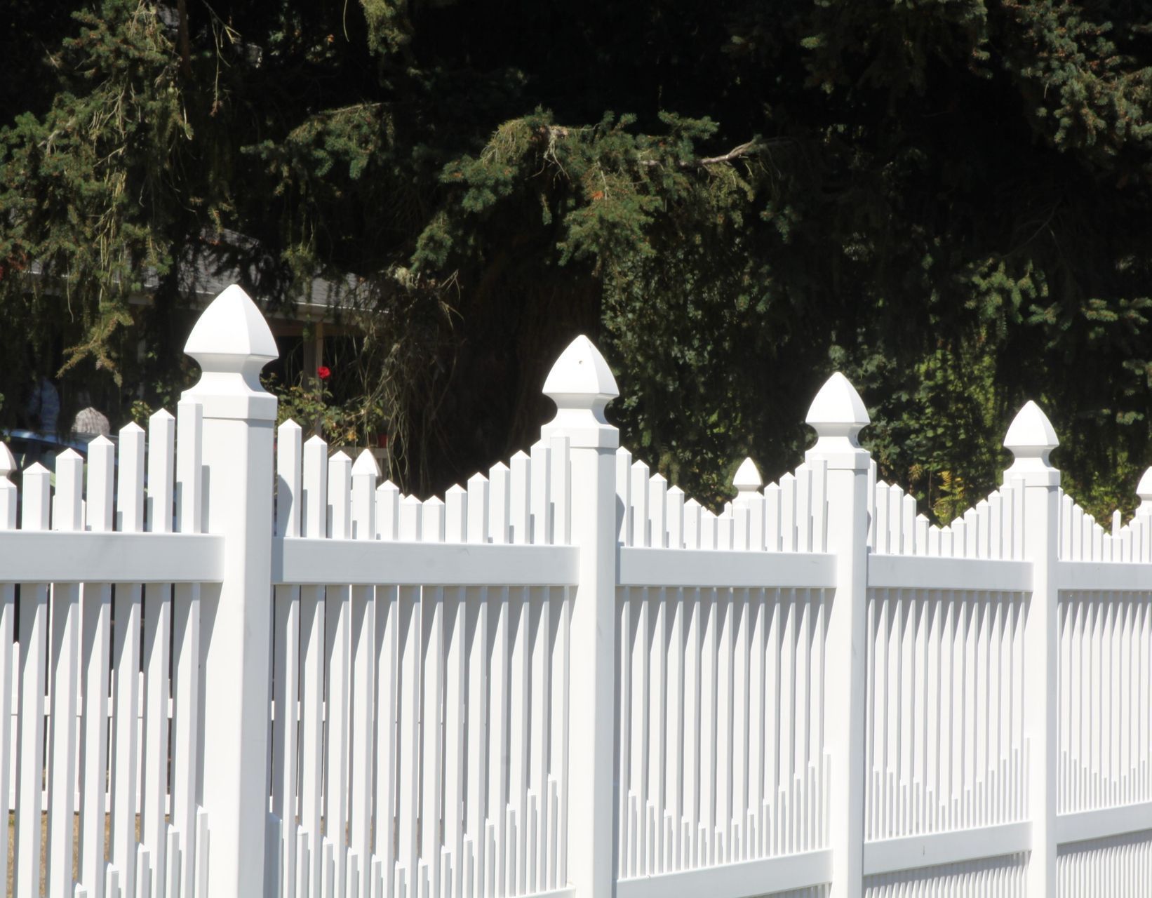 A white picket fence with trees in the background